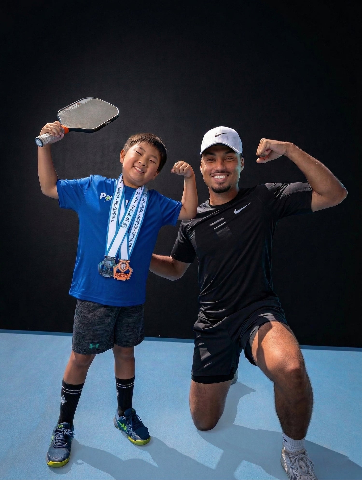 A young pickleball player celebrating with a coach
